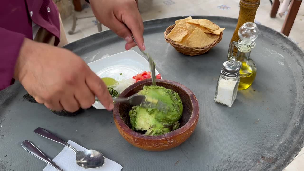 在墨西哥巴利亚多利德的一家露天餐厅里，服务员在餐桌旁准备鳄梨酱视频下载