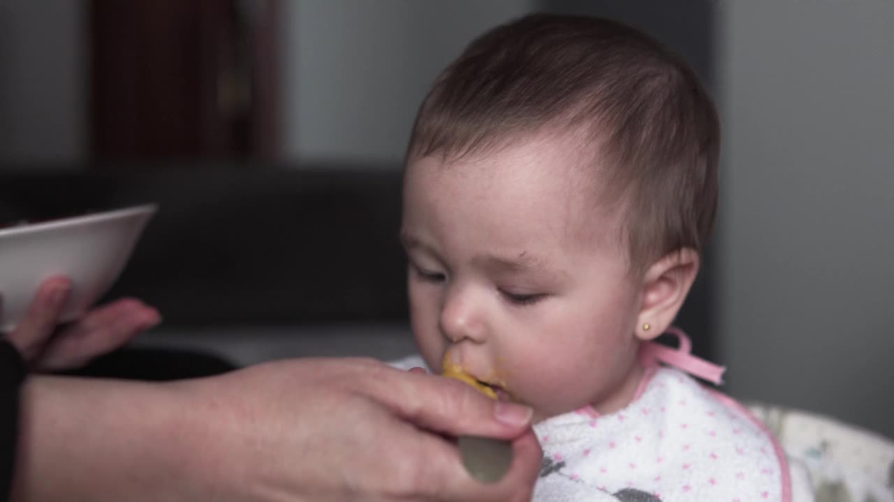 母亲正在给她的小女儿喂蔬菜粥视频素材