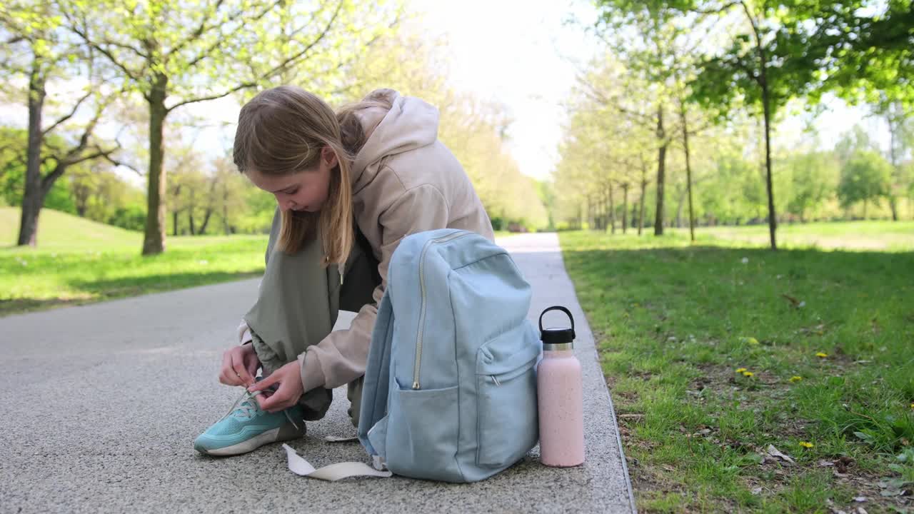 可爱的小女孩在夏日公园系鞋带视频下载