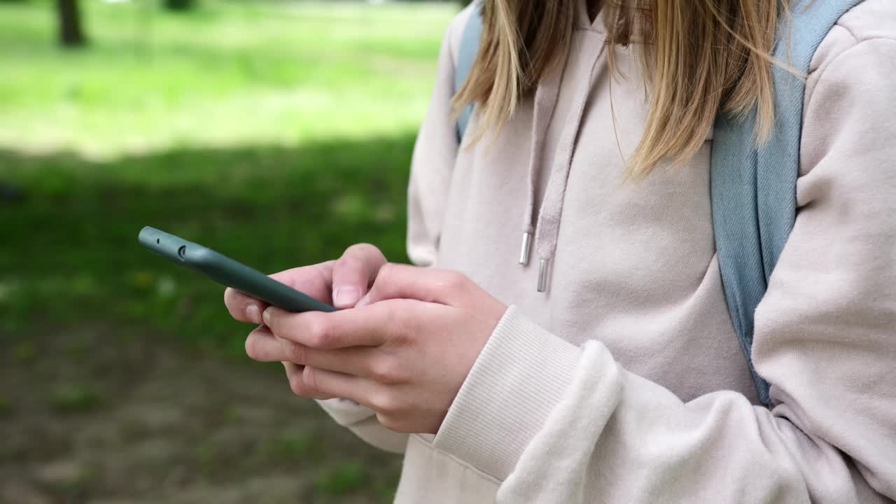 小女生在公园里用智能手机打字视频素材