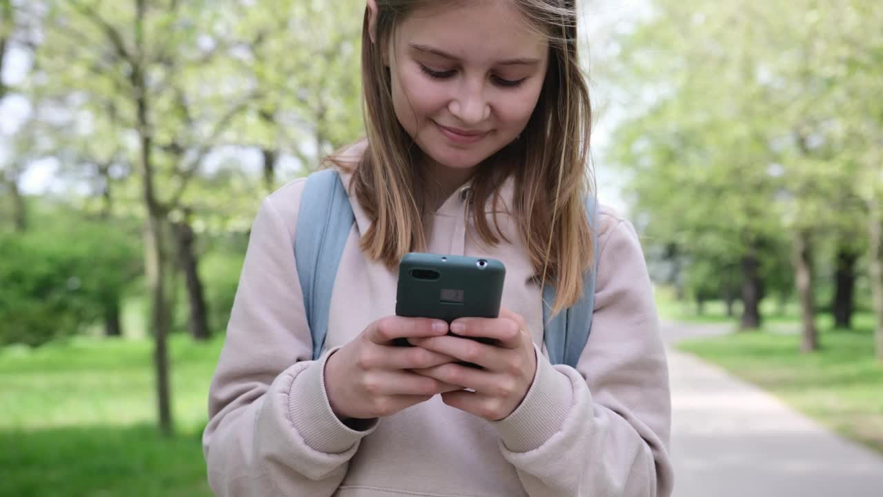 可爱的小女孩在公园里玩智能手机视频下载
