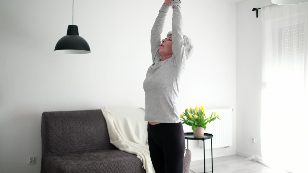白发活跃的老年妇女练习瑜伽姿势和放松在家里视频素材