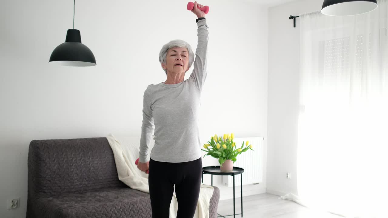 迷人的白发活跃的老年妇女在家用哑铃做健身运动视频下载