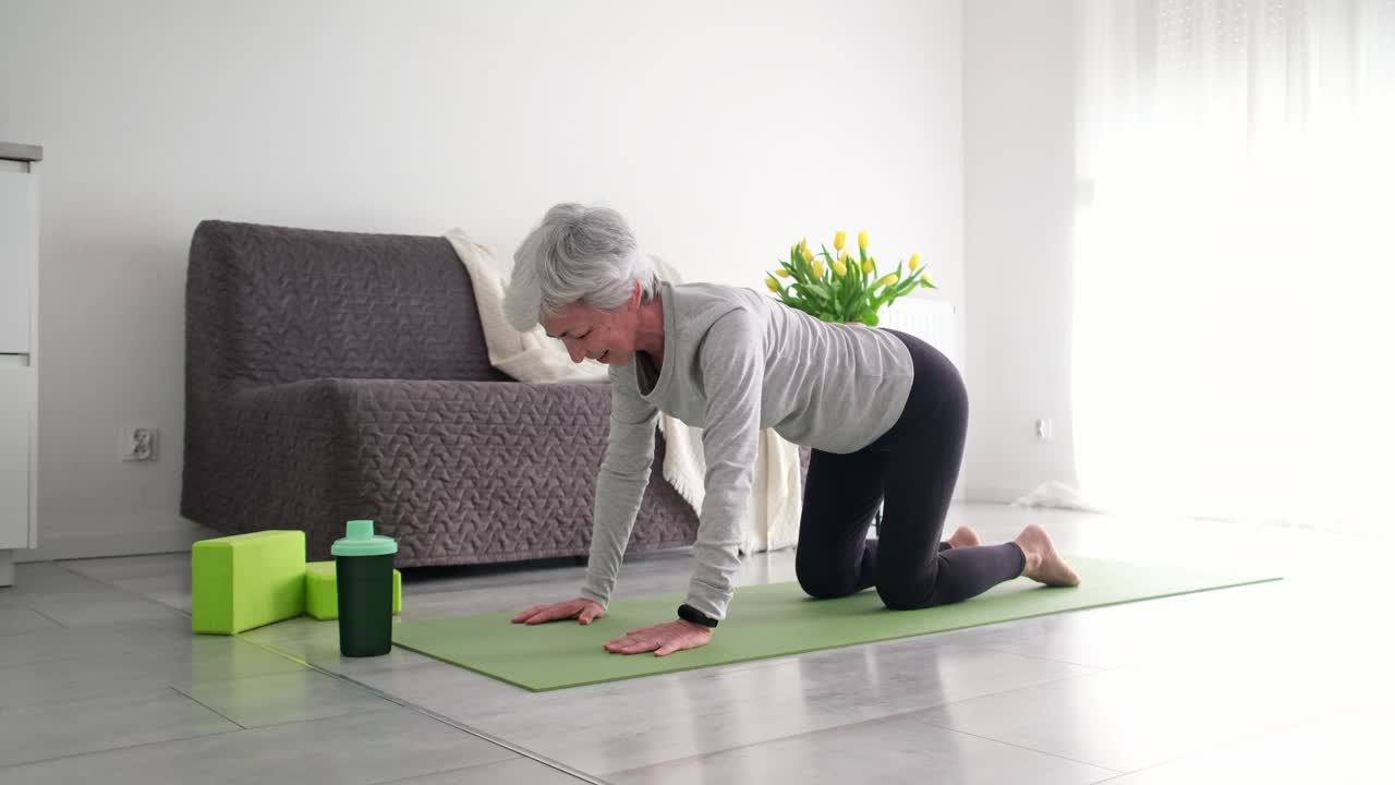 积极的老年妇女在家练习瑜伽视频素材