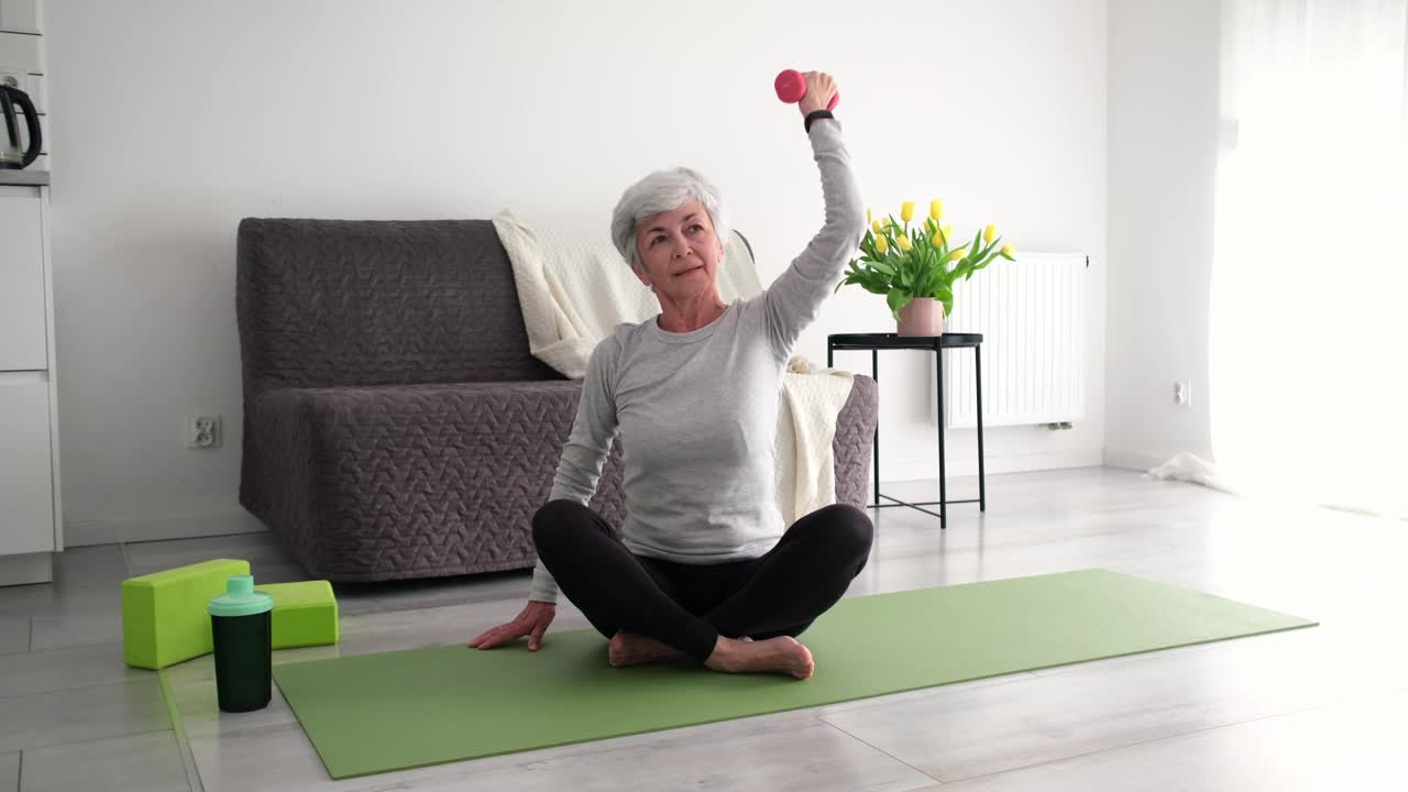 美丽的老年妇女练习健身训练，用哑铃做运动视频下载