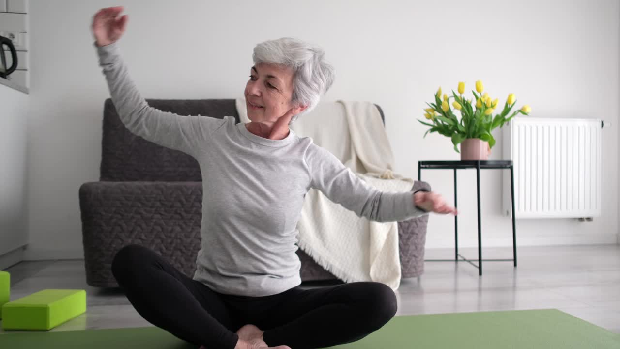 迷人的白发老年妇女在家里练习健身训练和侧弯拉伸视频素材