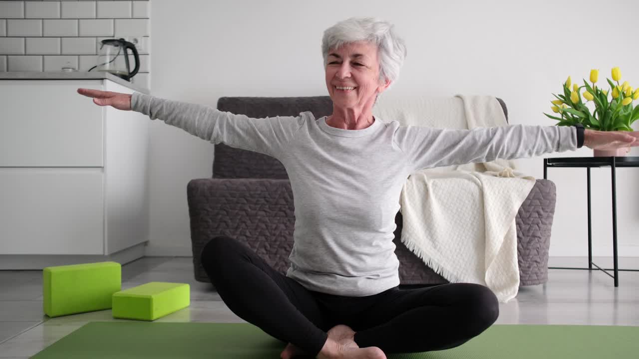 迷人的白发老太太在家练习健身训练和瑜伽视频素材