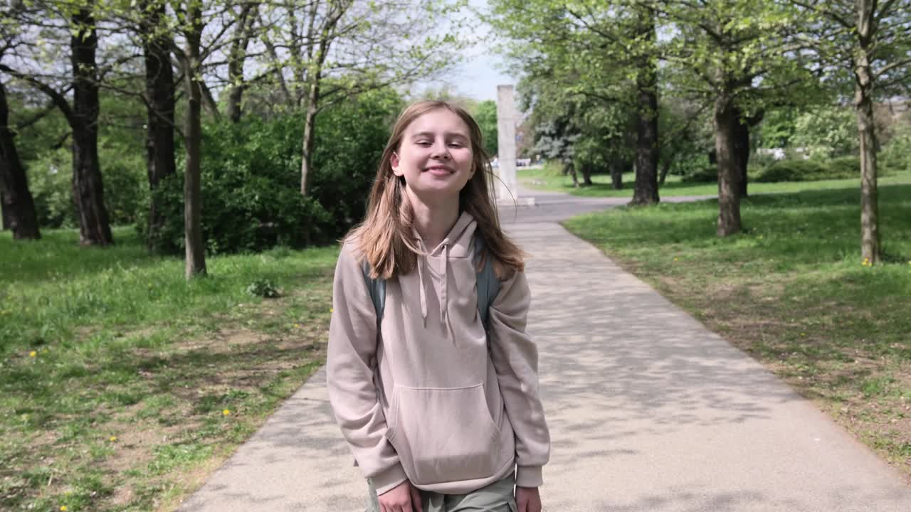 夏天，可爱的微笑小女孩走在公园里，看着镜头视频素材