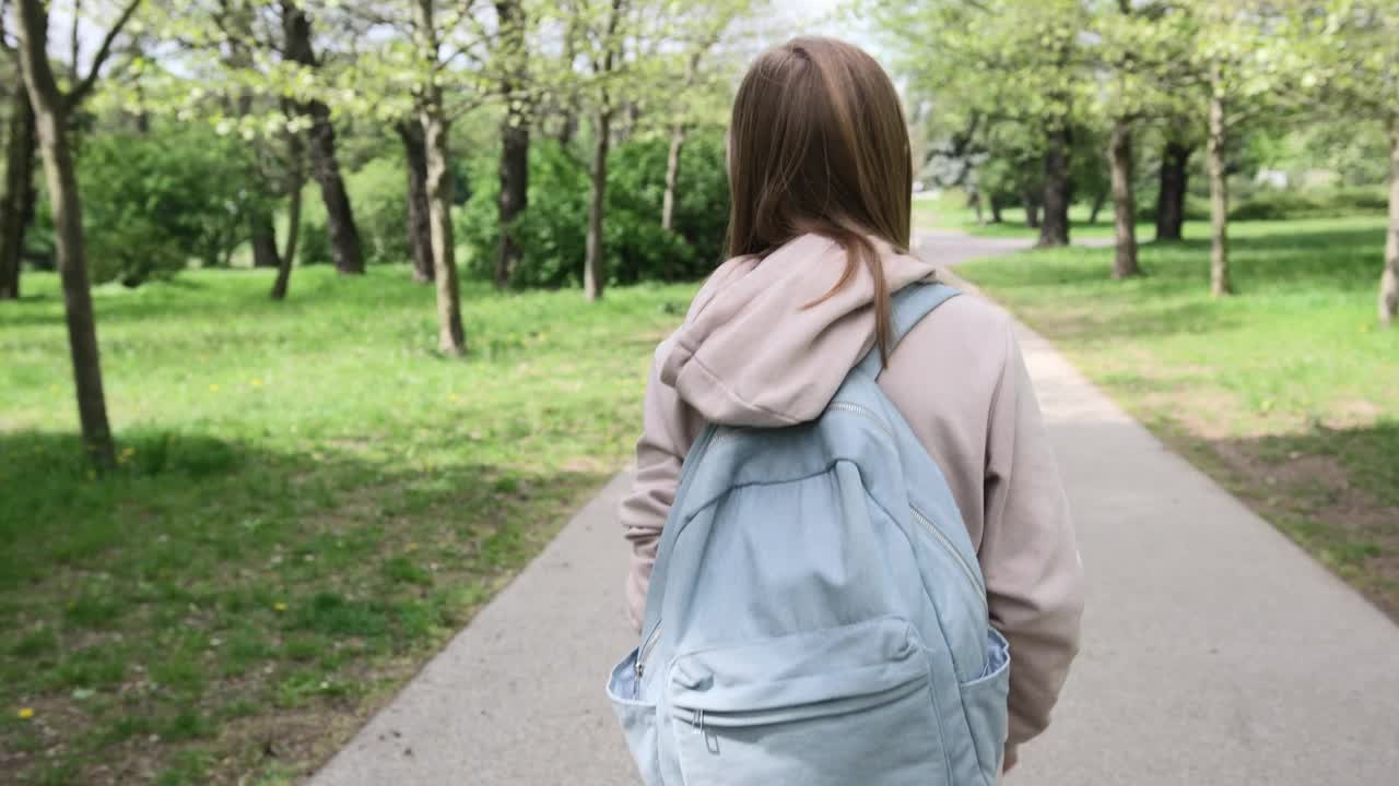 课后背着书包在公园散步的小女孩视频下载