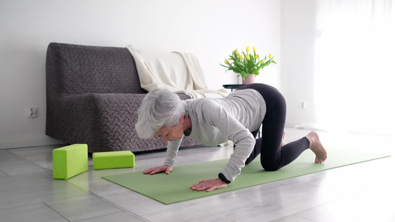 白发老人在家练习瑜伽和伸展运动视频素材