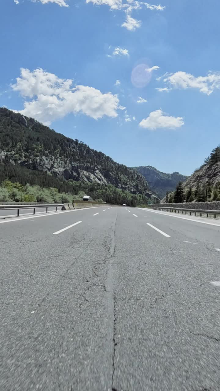 这是一幅令人惊叹的景色，一条道路蜿蜒穿过森林茂密的山区，雄伟的山脉隐约出现在背景中视频素材