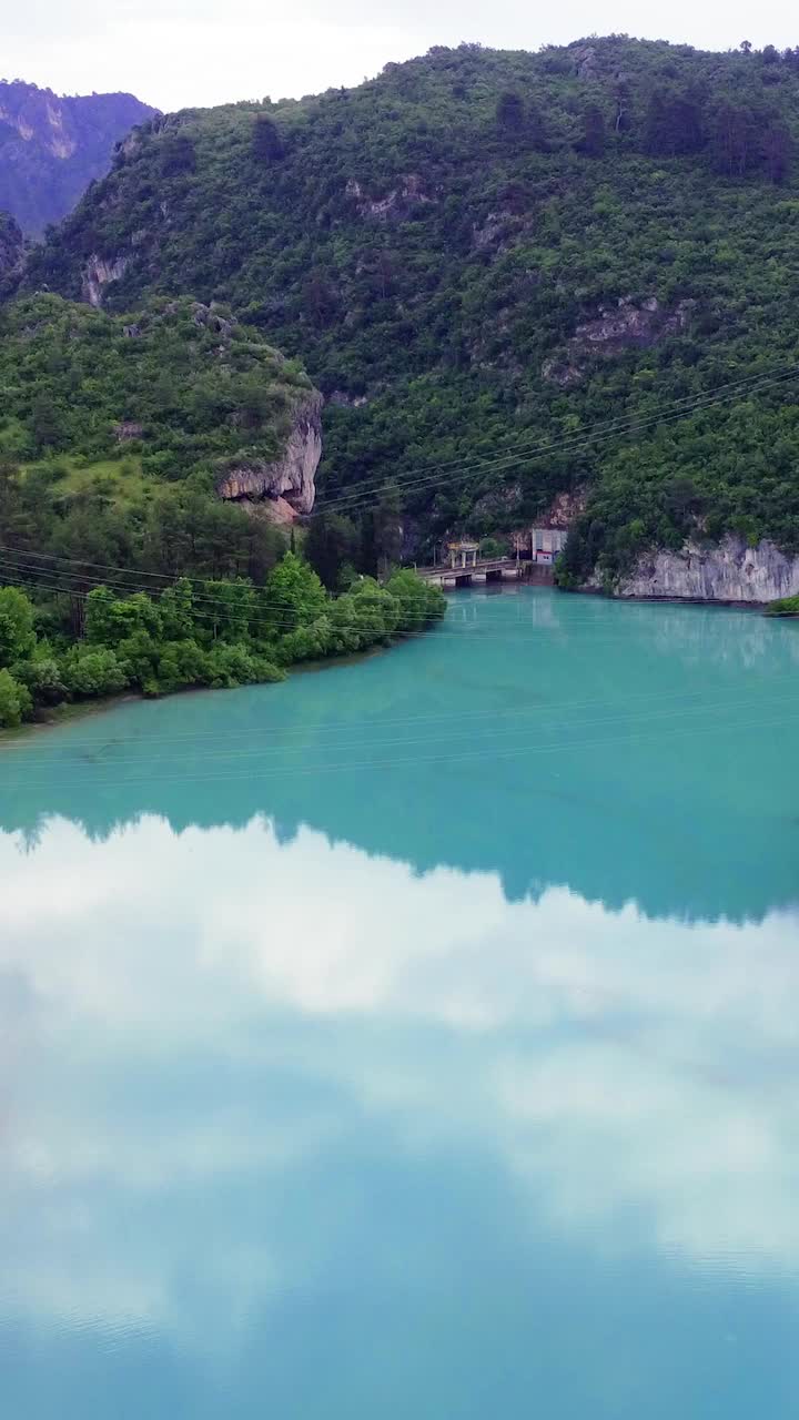 发现一个宁静的山湖坐落在参天大树和雄伟的山峰茂密的森林视频素材