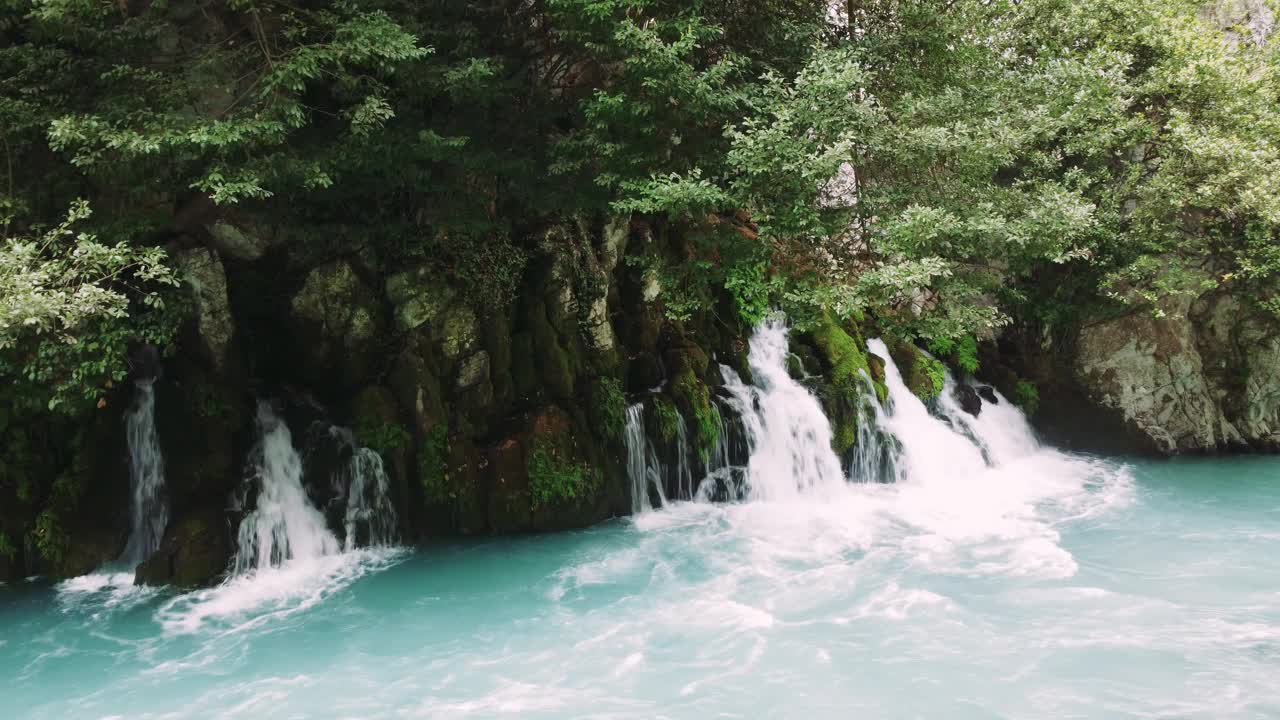 体验小瀑布的魔力，汇入湍急的绿松石河视频素材