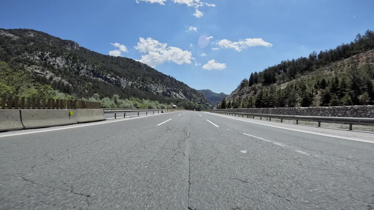 这是一幅令人惊叹的景色，一条道路蜿蜒穿过森林茂密的山区，雄伟的山脉隐约出现在背景中视频素材