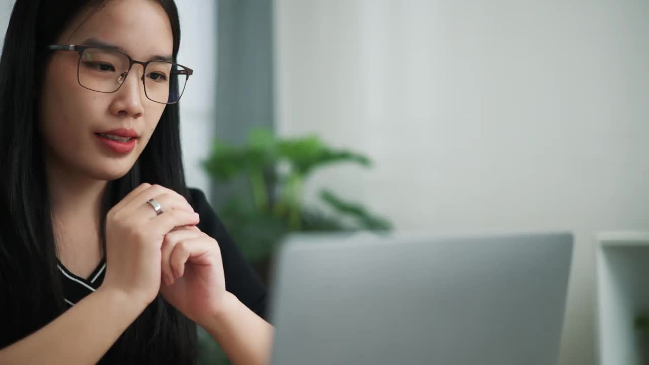 戴眼镜的女商人正在检查文件，并通过视频会议与同事交谈。视频素材