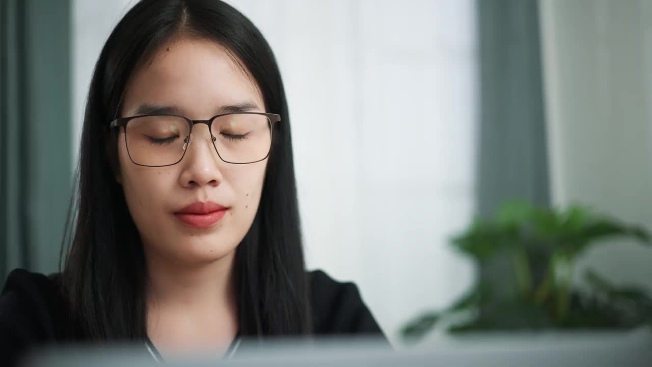 戴眼镜的女商人正在检查文件，并通过视频会议与同事交谈。视频素材