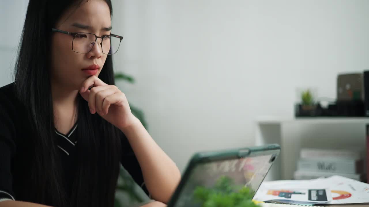 戴眼镜的女商人使用笔记本电脑，看起来很担心。视频素材