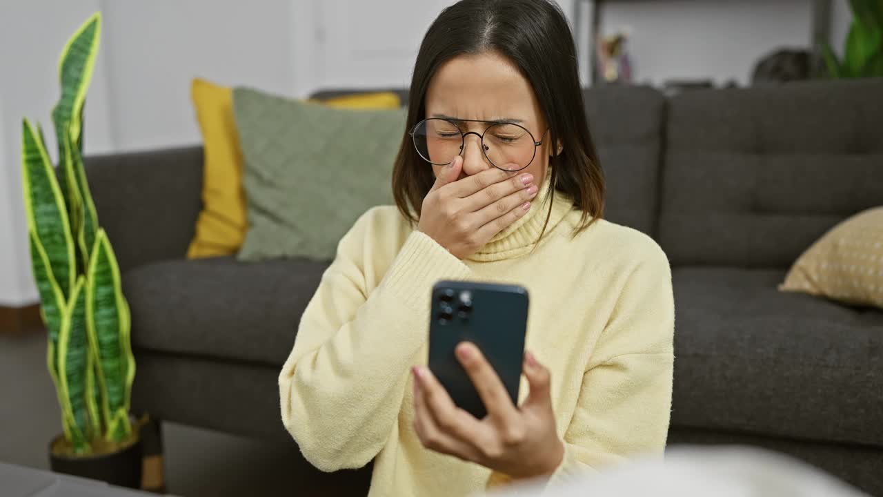 年轻的西班牙裔女子拿着药瓶，在室内客厅看着手机。视频素材