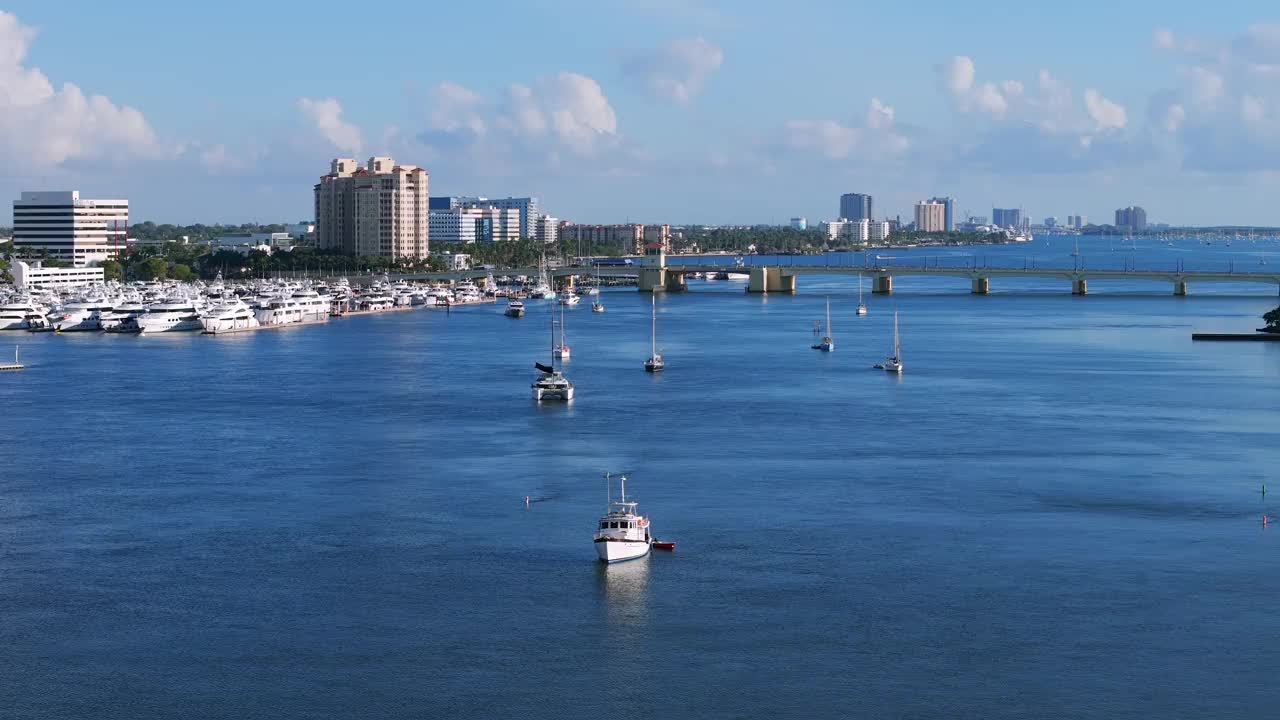 多艘船和游艇停泊在水中的海滨美景。建筑背景，包括暗示城市沿海地区的高层建筑视频素材