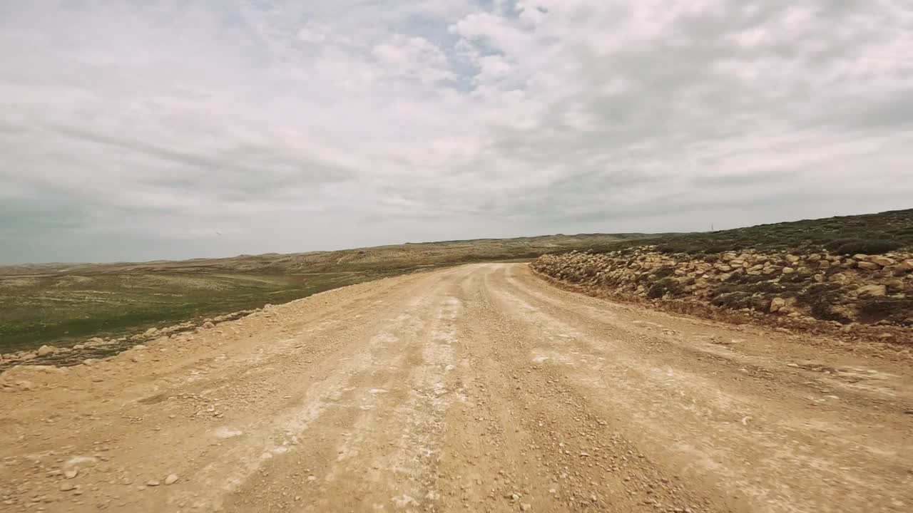 探索一条蜿蜒的土路，坐落在偏僻的地方，周围是令人惊叹的山景。体验驾车穿越未知的快感视频素材