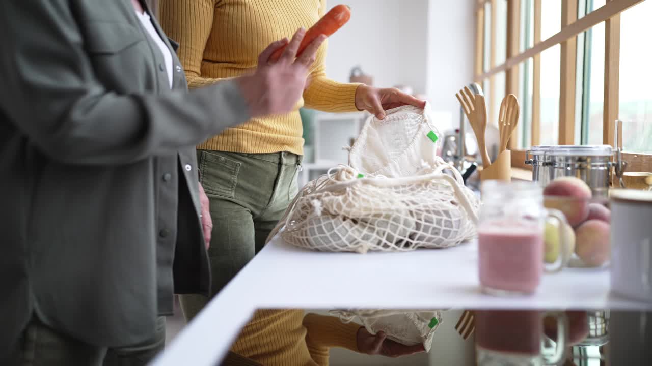 女儿和年长的母亲在自家厨房里拆菜视频素材