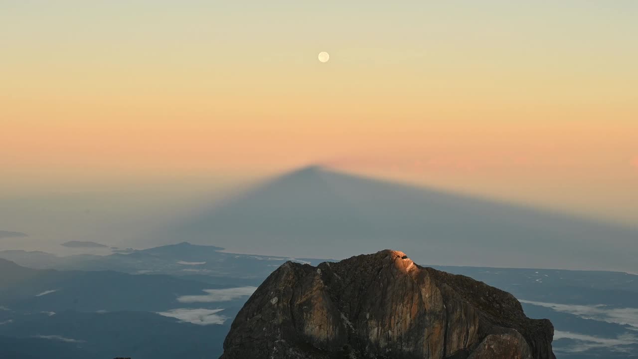 日出时，月亮从基纳巴卢山的阴影中升起。基纳巴卢山是东南亚最高的山之一。视频素材