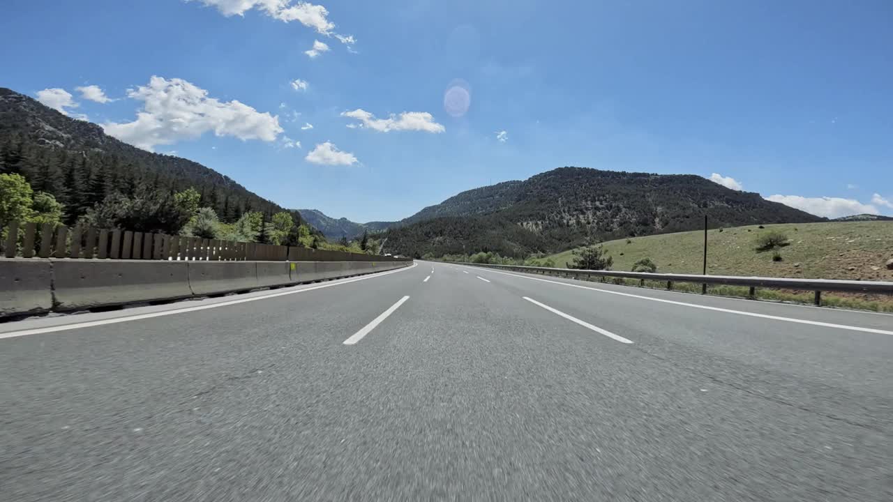 行驶在蜿蜒的道路上，郁郁葱葱的森林和高耸的山脉为背景，广阔的大自然展现在令人叹为观止的景色中视频素材