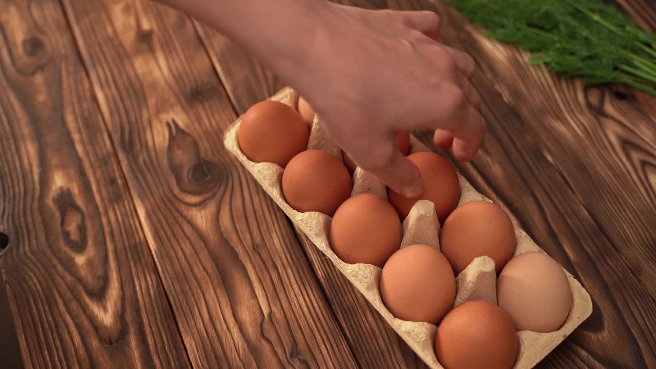 一个人小心地从纸盒里取出一个鸡蛋。产品质量评估视频素材