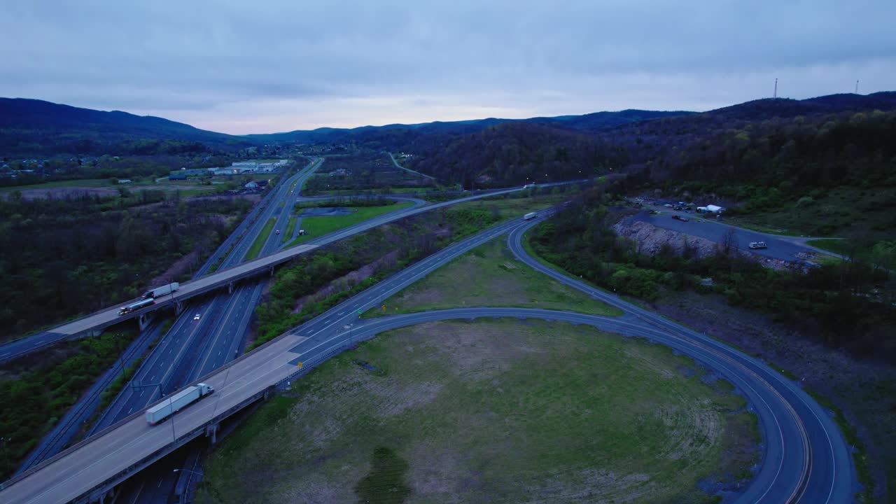 航拍傍晚拍摄的高速公路和半卡车在I-80在宾夕法尼亚州周围的绿色植物。视频素材