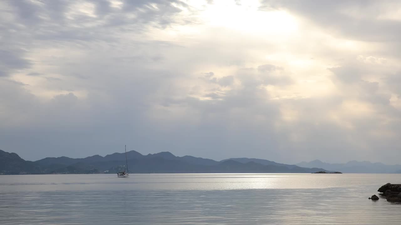 一艘在日出时缓缓驶离海岸的帆船视频素材