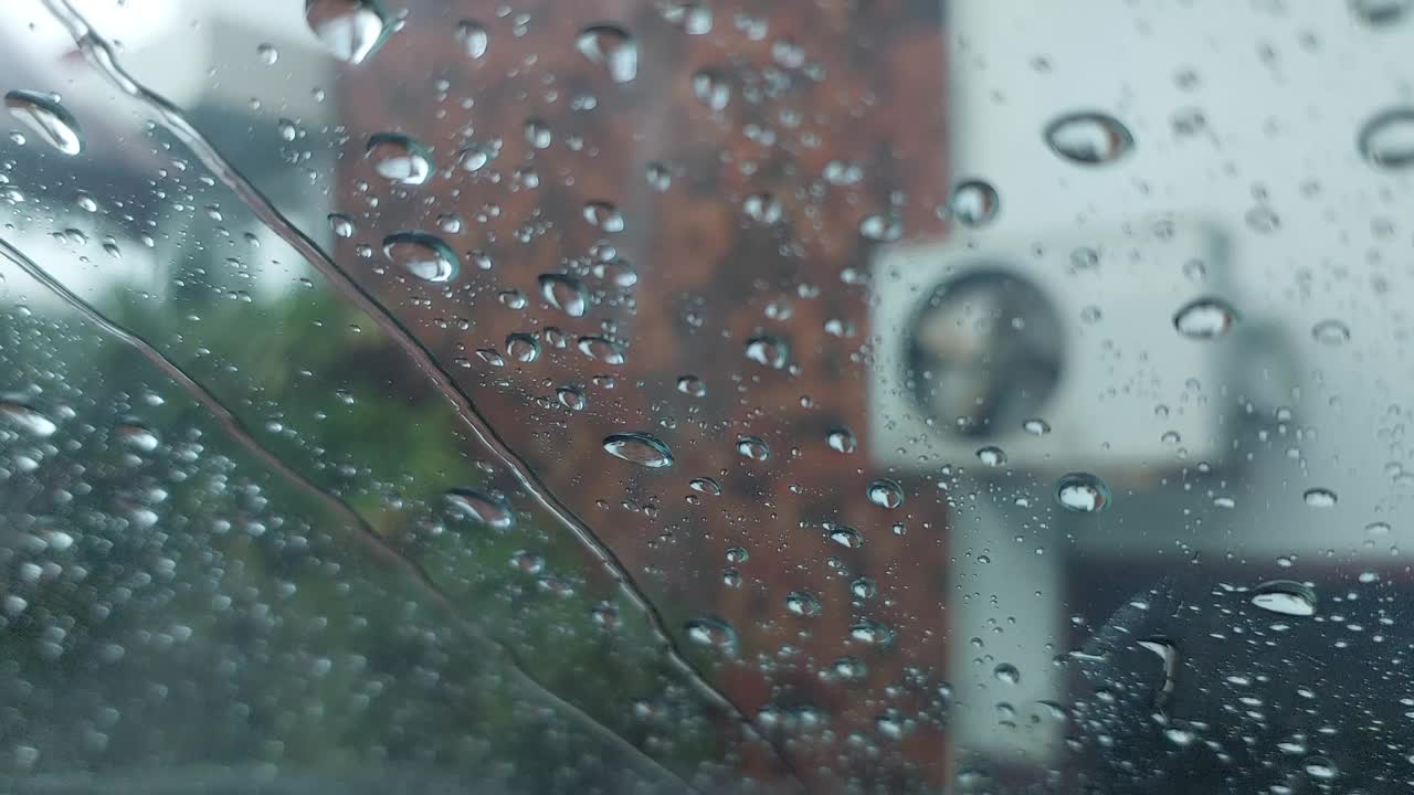 特写镜头透过雨点流动的背景。视频下载