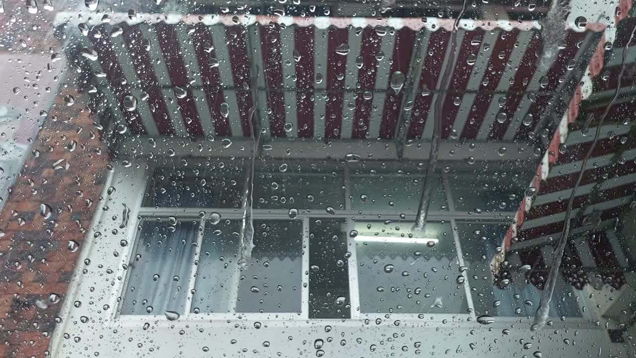 特写镜头透过雨点流动的背景。视频下载