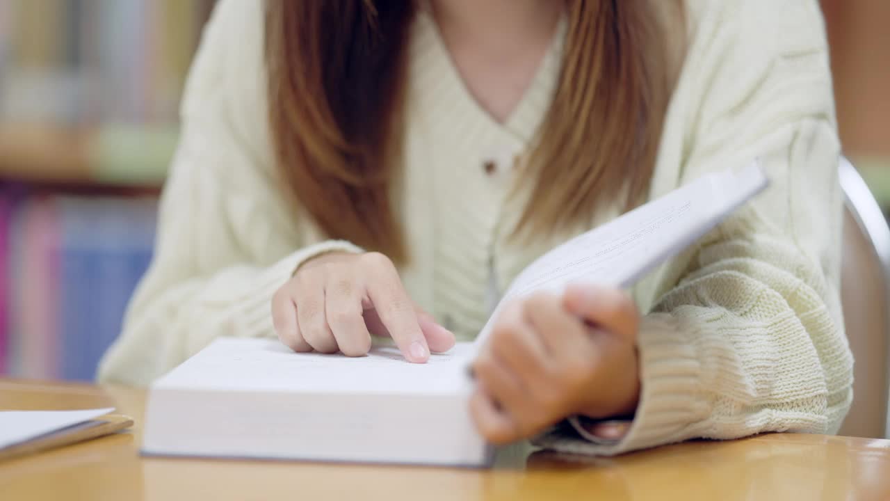 一个女孩正在看书，她的手放在书页上视频素材