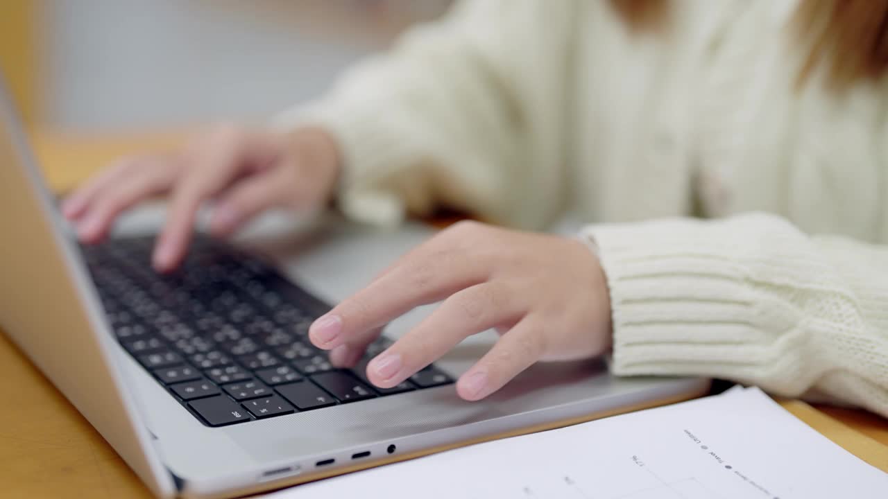 一个人穿着白毛衣在笔记本电脑上打字视频素材