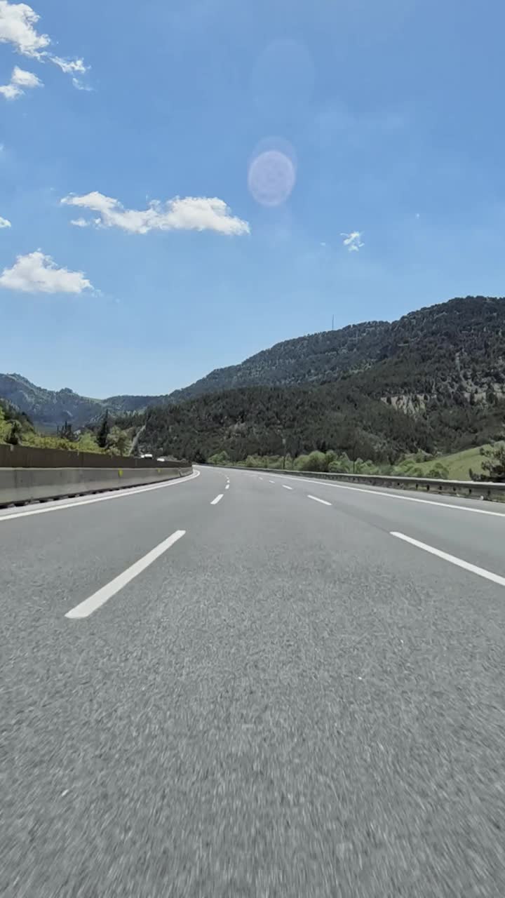 行驶在蜿蜒的道路上，郁郁葱葱的森林和高耸的山脉为背景，广阔的大自然展现在令人叹为观止的景色中视频素材