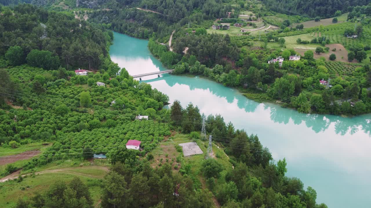 从空中俯瞰，一个宁静的绿松石山湖被高耸的山峰环绕，沐浴在柔和的晨光中视频素材