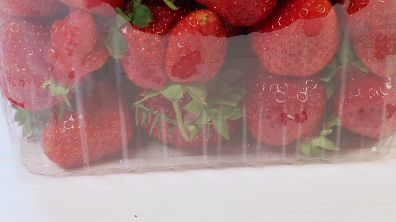 木质背景上包装的新鲜红草莓的慢镜头。视频下载