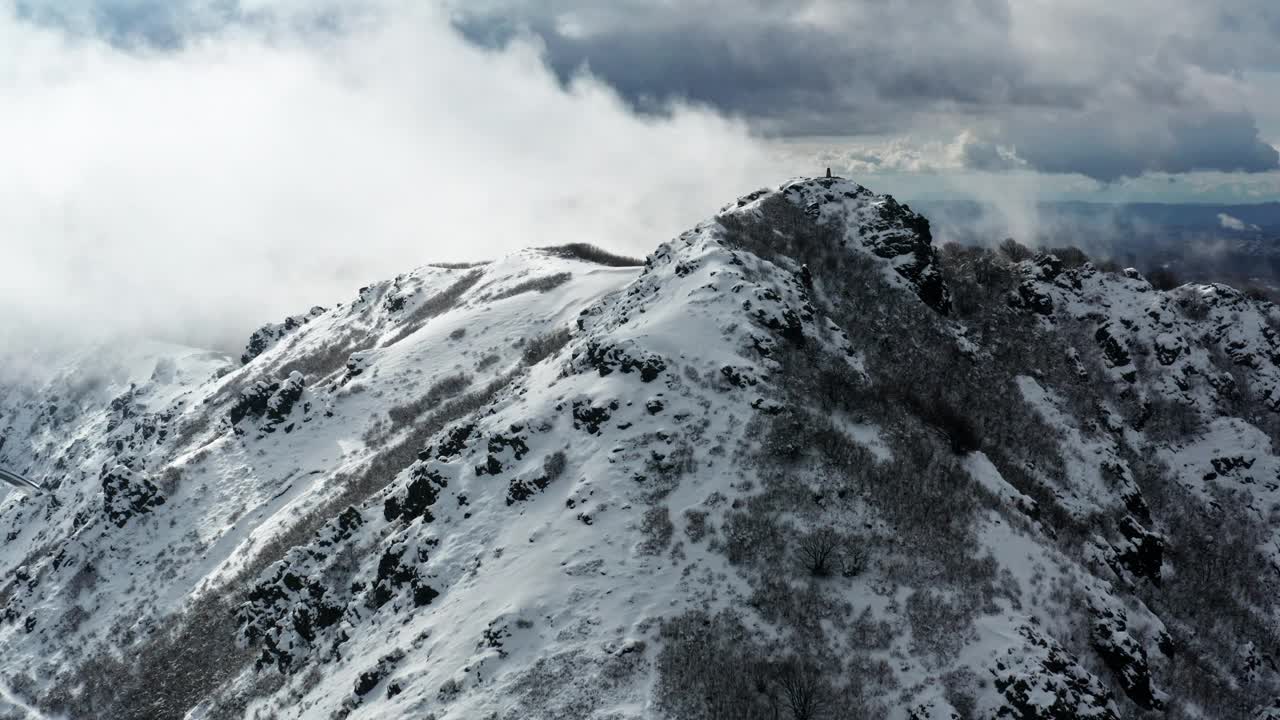 白雪覆盖的山峰笼罩在云中，航拍捕捉崎岖的地形和宁静的景观视频素材