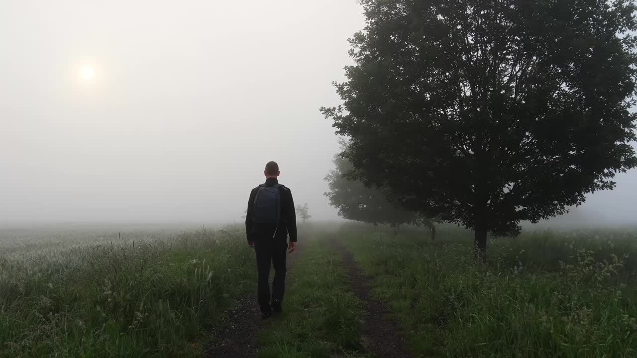 一个背着双肩包的人在宁静的晨雾中漫步。捷克景观视频下载