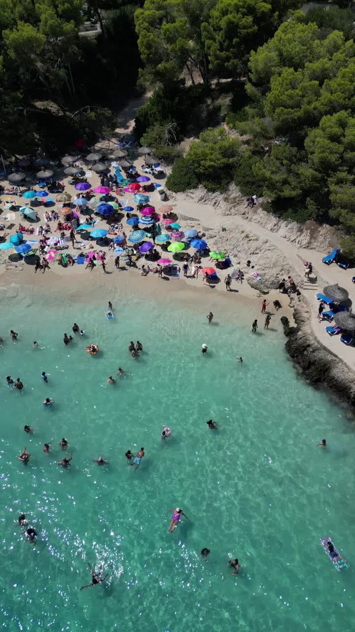 西班牙马略卡岛，伊莱塔斯海滩上清澈碧绿的海水和日光浴者的鸟瞰图视频素材