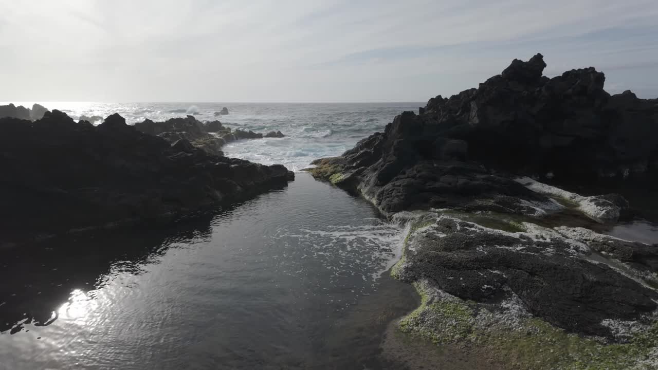 崎岖的火山岩和潮汐池在莫斯蒂罗斯，圣米格尔与动态海浪视频素材