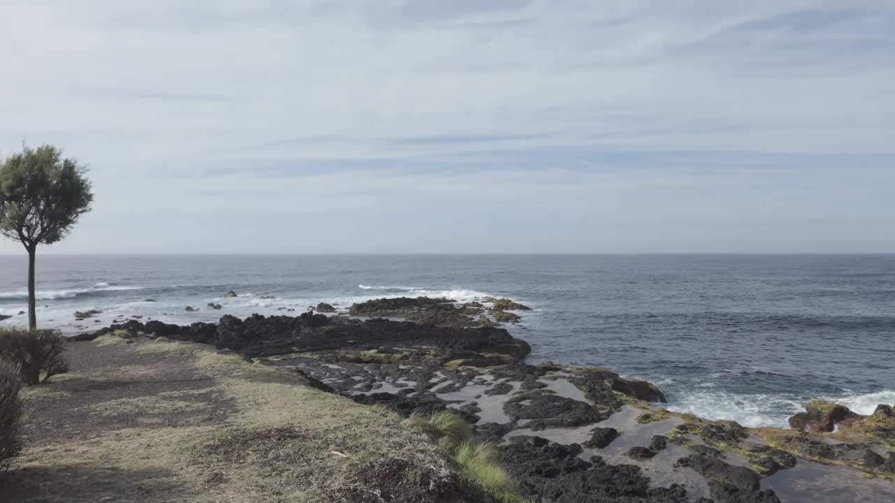 莫斯泰罗斯的广角镜头，圣米格尔海岸，波涛汹涌的大海和多云的天空下的岩石海岸线，自然色彩，白天视频素材