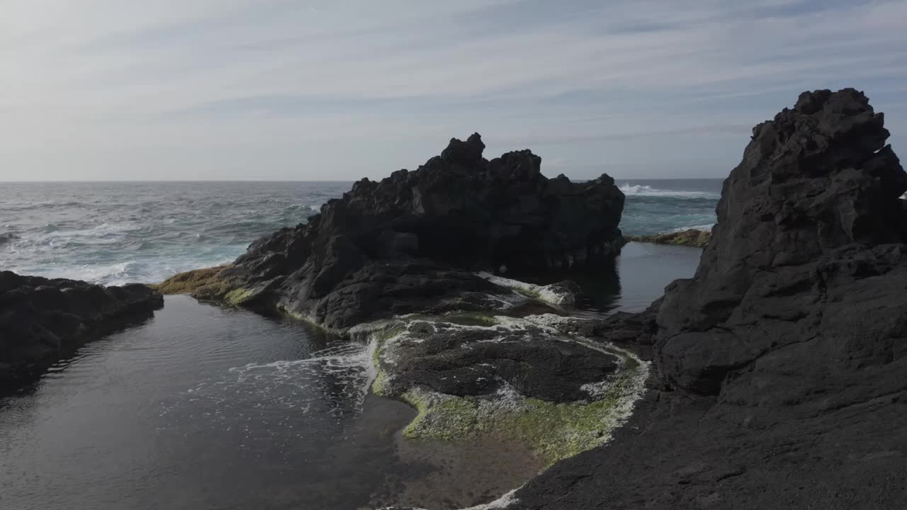 多云的天空下，圣米格尔海滩上崎岖的火山岩层和潮汐池视频素材