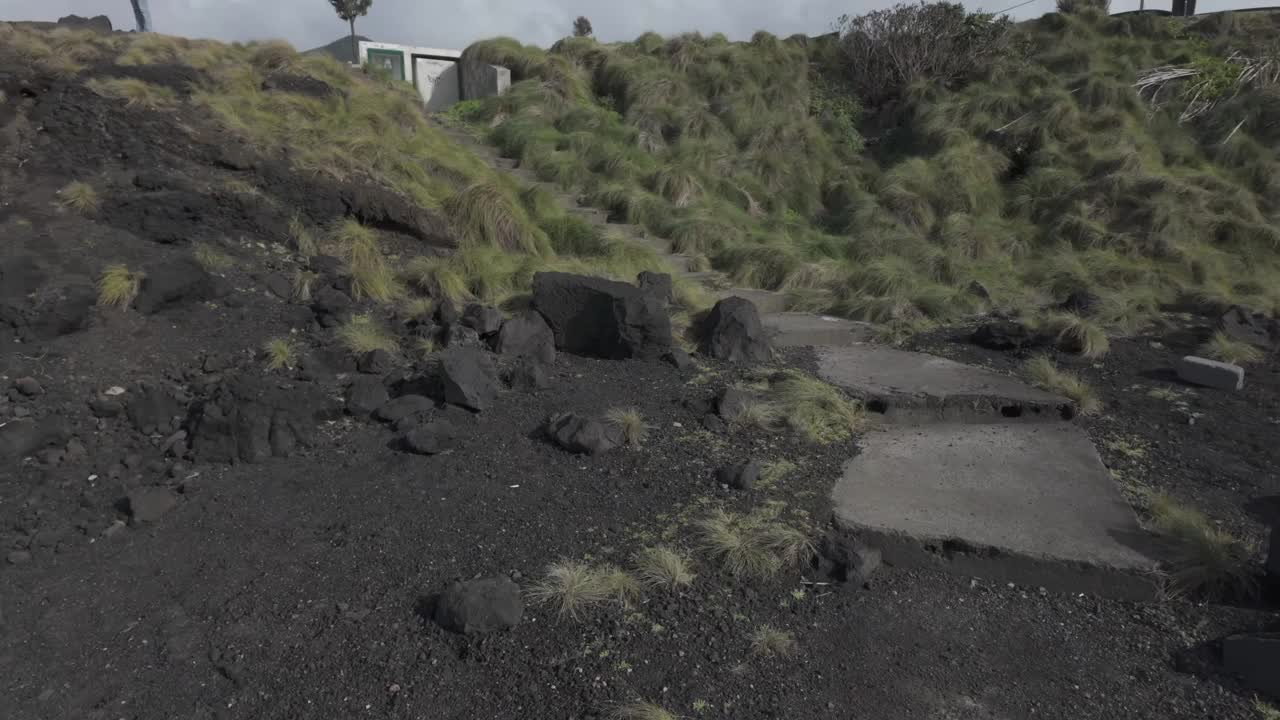 黑色火山岩和郁郁葱葱的绿草覆盖在圣米格尔的莫斯泰罗斯的山坡上，在纹理上形成鲜明的对比，广角镜头视频素材