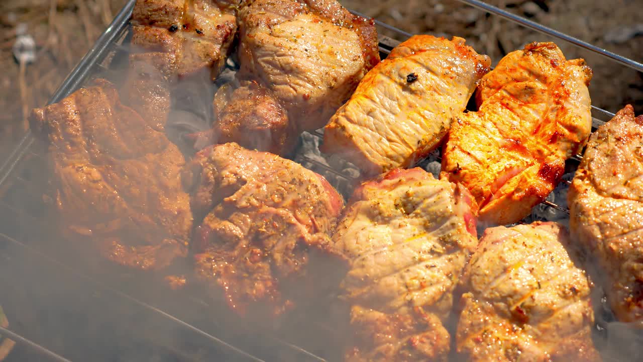 近距离烤肉。多汁的猪肉块在热烤架上滋滋作响。肉的烹饪完美，烧焦的外观美味视频素材