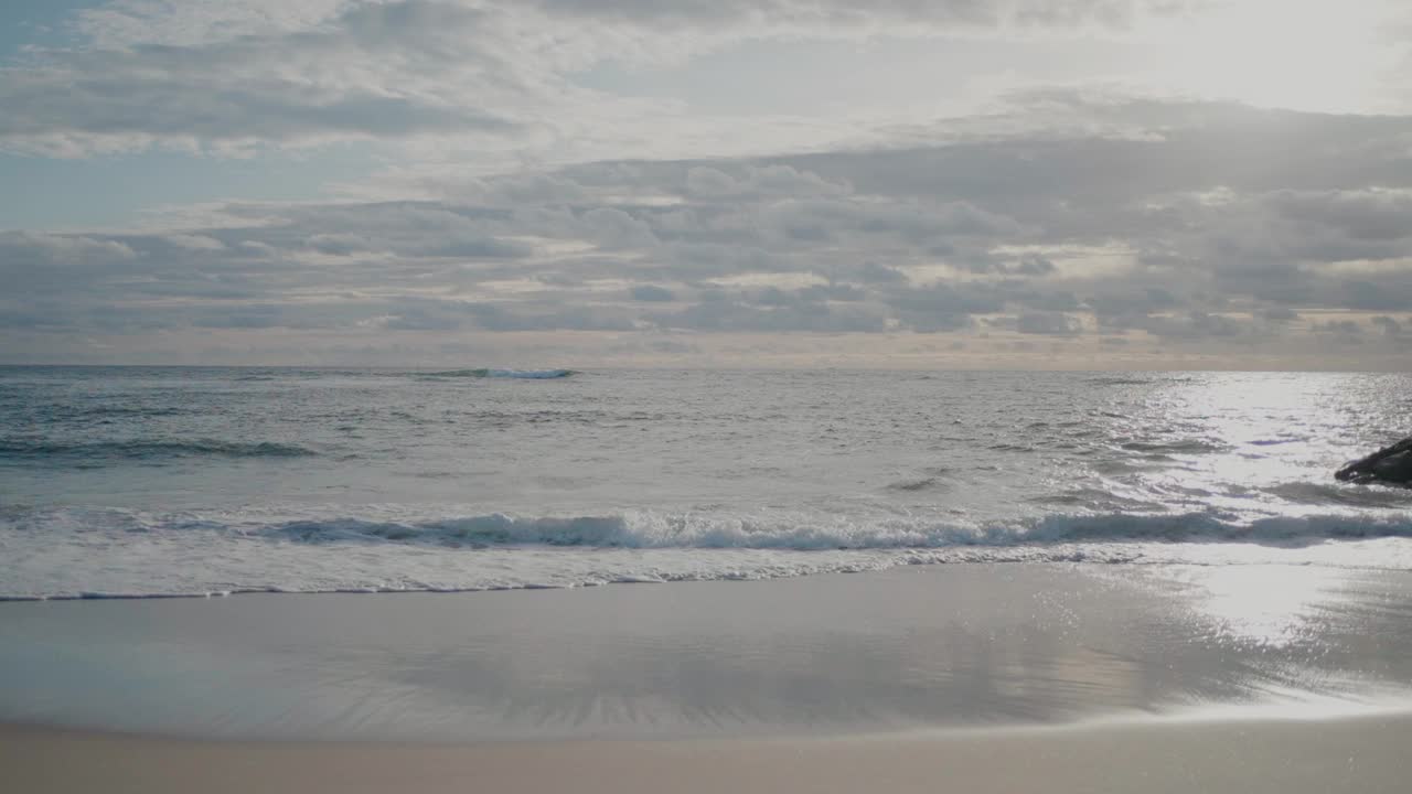 温和的海浪拍打在多云的天空下的沙滩海岸在奥瓦尔，葡萄牙。视频素材