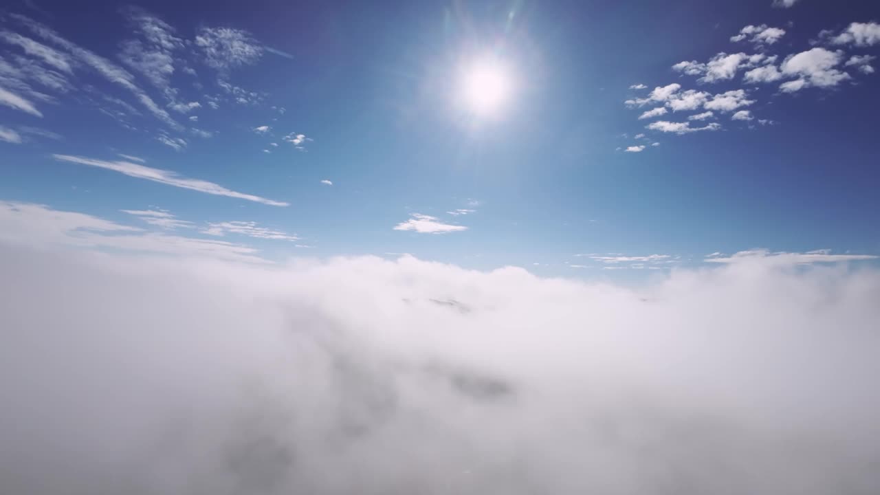 我们飞过云层。蓝天有云，有太阳。在一个晴朗的日子里，在云层中飞行的4K视频，透过云层看到道路视频素材