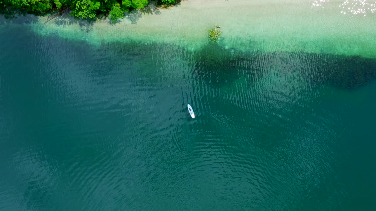 夏季，斯洛文尼亚绿色湖水上的竖桨板鸟瞰图视频下载