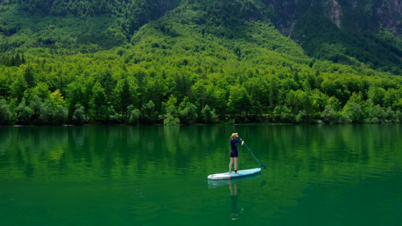 鸟瞰图上的人在站立板上划桨在斯洛文尼亚的山湖视频素材