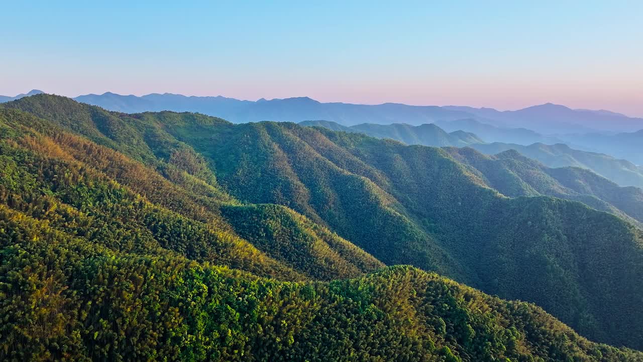 鸟瞰日落时的绿色森林和山地自然景观视频素材